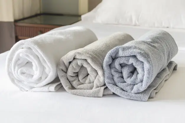 Clean bright bathroom with fresh folded white towels arranged hotel-style